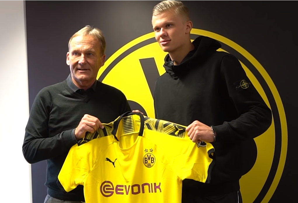 套娃，久保建英坐在涩谷的大久保建英像下握着一个小久保建英（久保建英坐在涩谷自己的巨型雕像下，手握迷你版的自己）